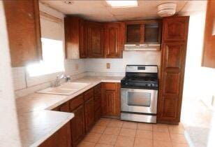 kitchen with stainless steel range, light tile patterned flooring, and sink