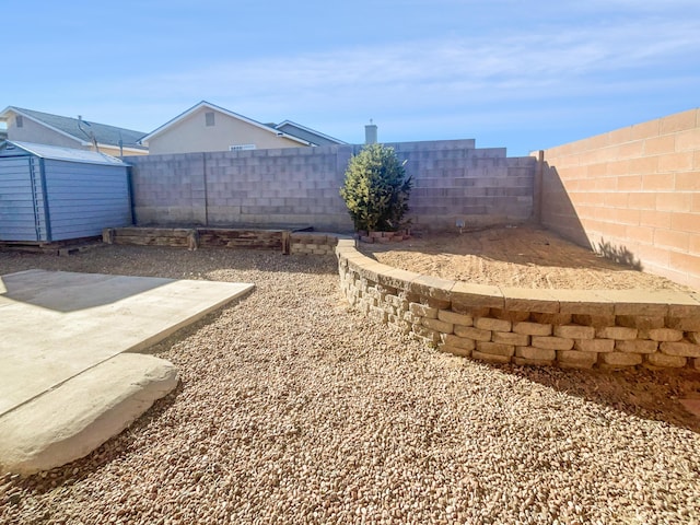 view of yard featuring a storage unit and a patio