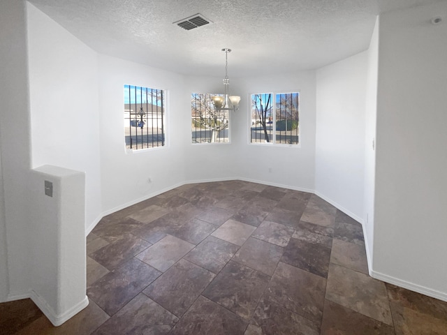 unfurnished dining area featuring a notable chandelier and a textured ceiling