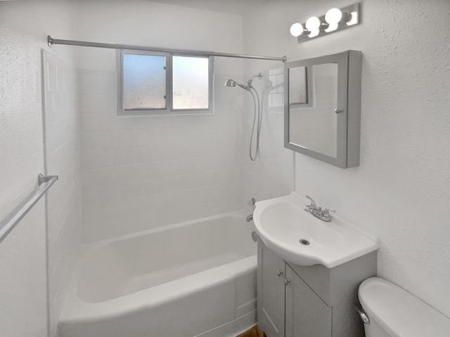 bathroom with a textured wall, shower / bathing tub combination, vanity, and toilet