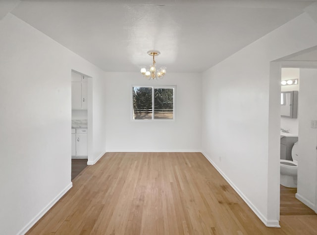 unfurnished dining area featuring a chandelier, light wood finished floors, and baseboards