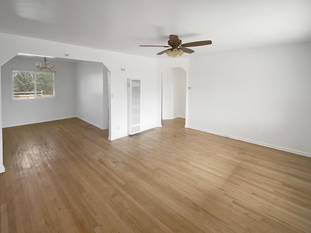 empty room featuring light wood-type flooring, visible vents, baseboards, and ceiling fan with notable chandelier