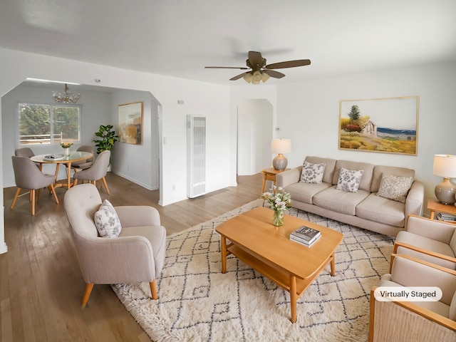 living area with ceiling fan with notable chandelier, wood finished floors, and visible vents