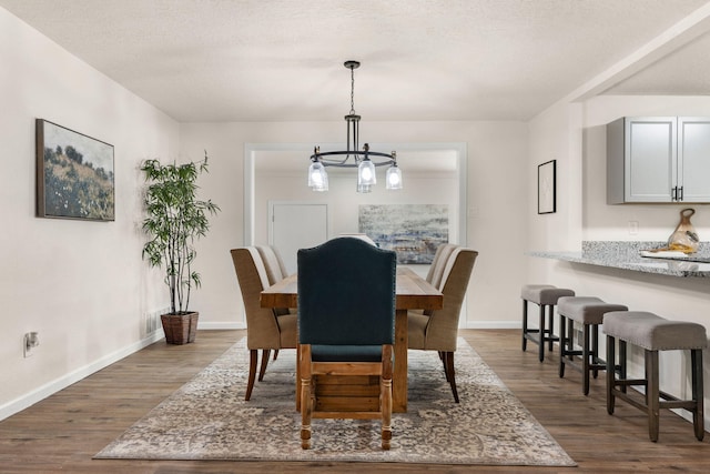 dining space featuring dark wood-type flooring, a notable chandelier, and a textured ceiling