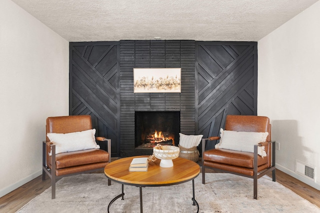 living area with wood-type flooring, a fireplace, and a textured ceiling