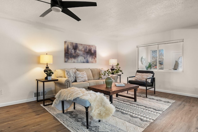 living room with ceiling fan, dark hardwood / wood-style flooring, and a textured ceiling