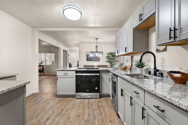 kitchen with sink, stainless steel range with electric cooktop, gray cabinetry, hanging light fixtures, and light wood-type flooring