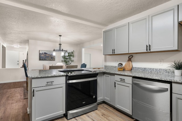 kitchen featuring gray cabinetry, light stone counters, kitchen peninsula, stainless steel appliances, and light hardwood / wood-style flooring