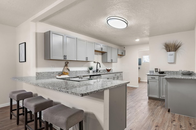 kitchen featuring gray cabinets, kitchen peninsula, and hardwood / wood-style floors