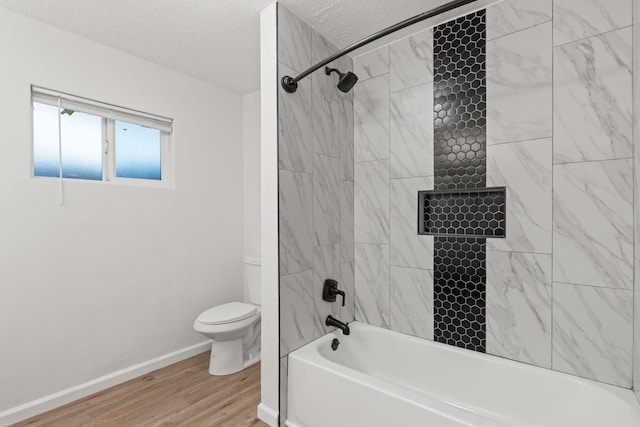 bathroom featuring tiled shower / bath, wood-type flooring, toilet, and a textured ceiling