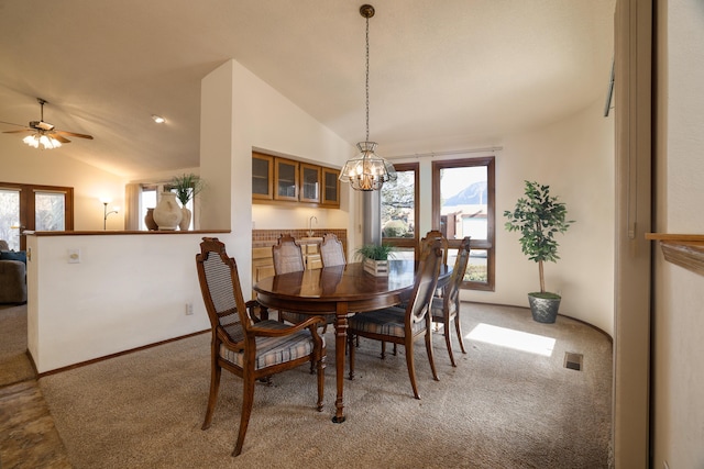 carpeted dining room featuring ceiling fan with notable chandelier and lofted ceiling