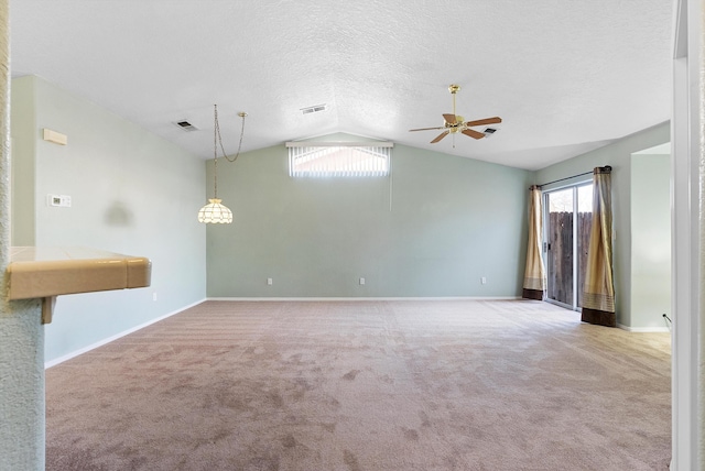 carpeted spare room with a textured ceiling, a healthy amount of sunlight, lofted ceiling, and ceiling fan