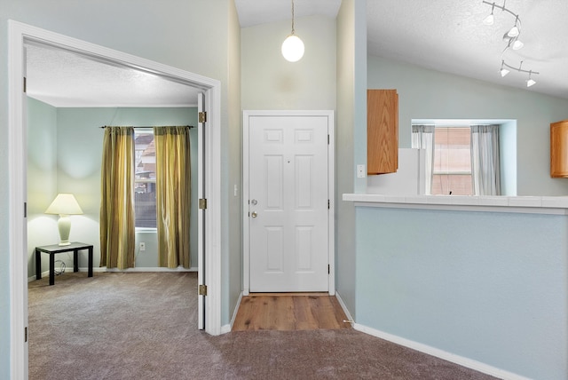 carpeted entryway with a textured ceiling and lofted ceiling