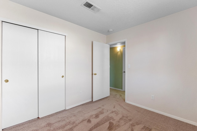 unfurnished bedroom featuring a closet and light colored carpet