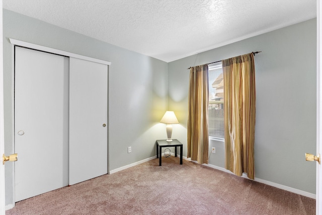 unfurnished bedroom with carpet floors, a textured ceiling, and a closet