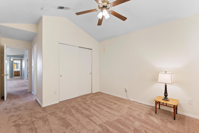 unfurnished bedroom with ceiling fan, a closet, vaulted ceiling, and light carpet