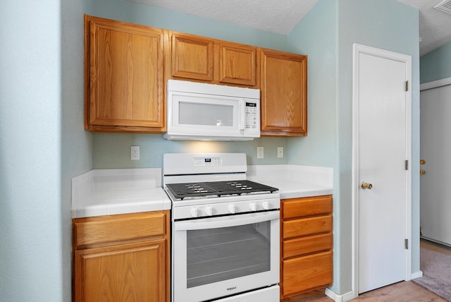 kitchen featuring tile counters, white appliances, and a textured ceiling