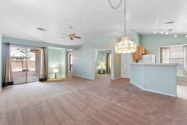 unfurnished living room featuring a textured ceiling, ceiling fan, lofted ceiling, and light colored carpet