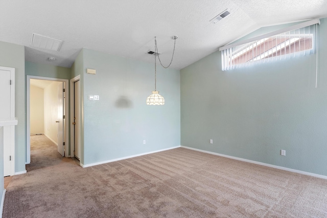 carpeted spare room featuring vaulted ceiling and a textured ceiling