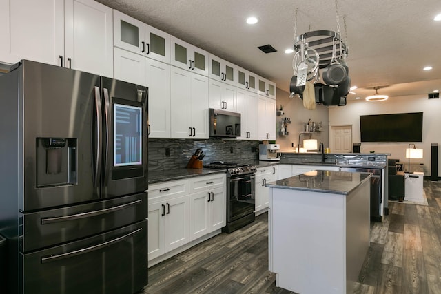 kitchen with white cabinets, stainless steel refrigerator with ice dispenser, a center island, and black range with gas cooktop