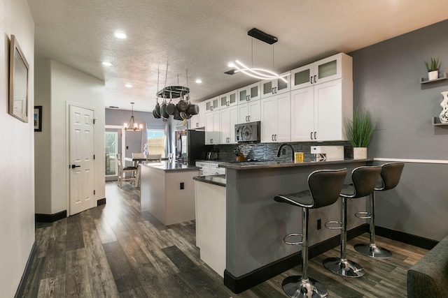 kitchen with kitchen peninsula, a center island, white cabinetry, and pendant lighting