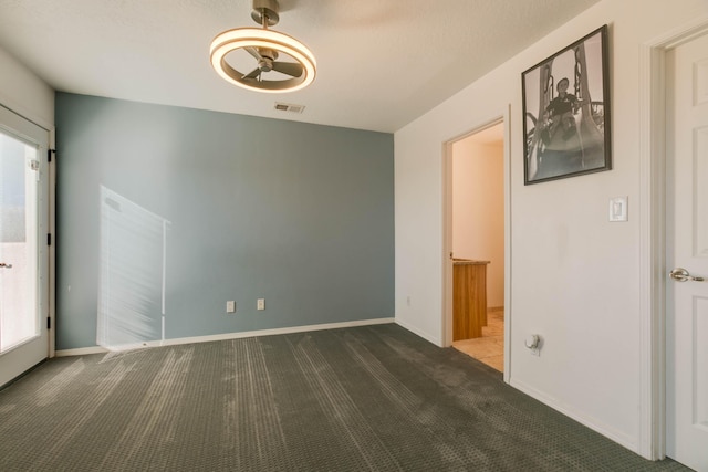 unfurnished room featuring dark colored carpet