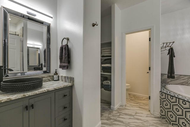 bathroom with toilet, vanity, and a bath