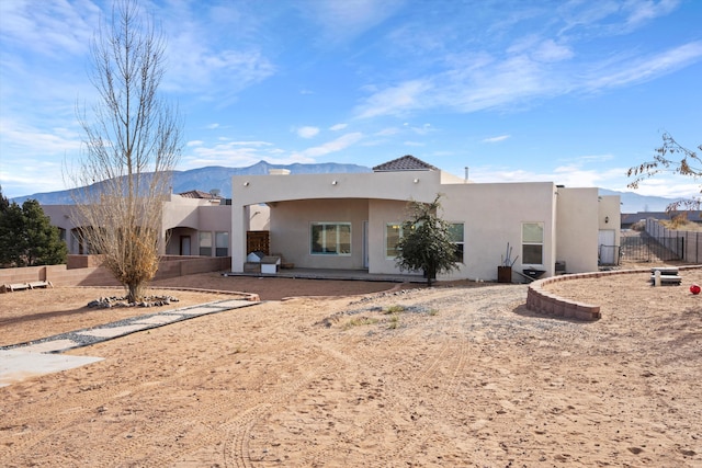 rear view of property with fence, a mountain view, and stucco siding