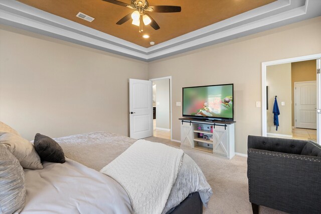 carpeted bedroom with ceiling fan and a tray ceiling