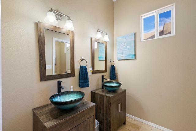 bathroom featuring baseboards, two vanities, a sink, and tile patterned floors