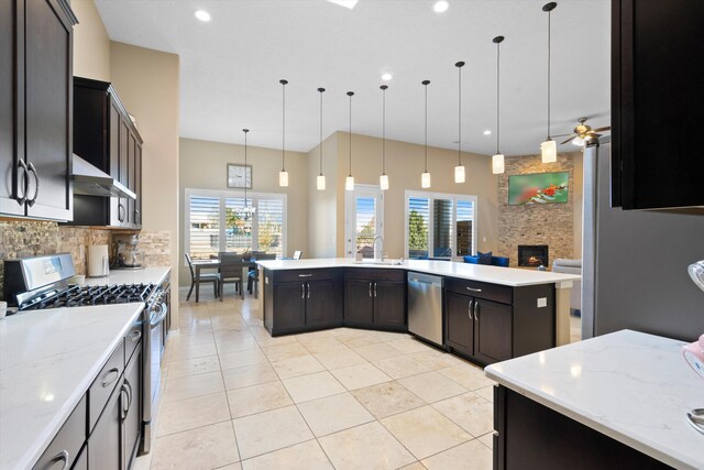 kitchen featuring hanging light fixtures, tasteful backsplash, a stone fireplace, and stainless steel appliances