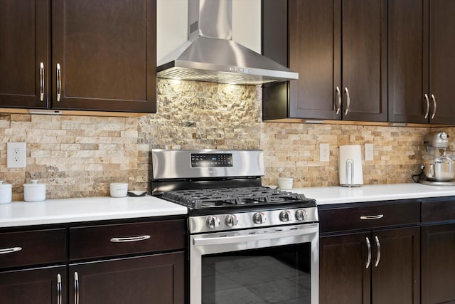 kitchen with dark brown cabinets, decorative backsplash, wall chimney exhaust hood, and gas stove