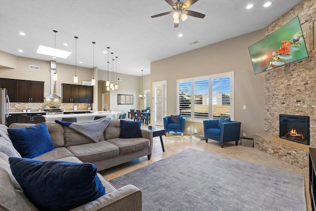 living room featuring a towering ceiling, light tile patterned floors, visible vents, and a stone fireplace