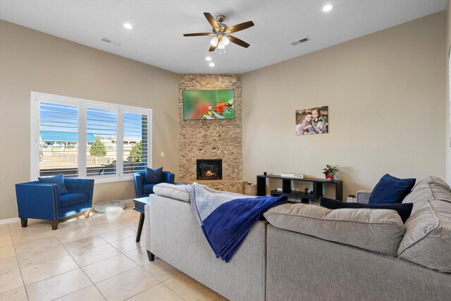 tiled living room featuring ceiling fan and a stone fireplace