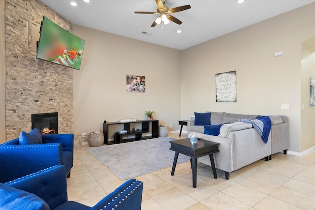 tiled living room featuring ceiling fan and a stone fireplace