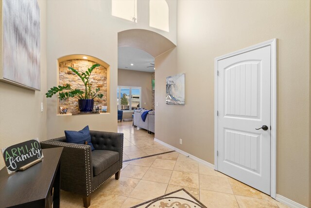 entryway with ceiling fan, light tile patterned flooring, and a high ceiling