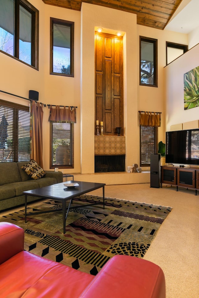 living room with wood ceiling, a towering ceiling, and carpet flooring