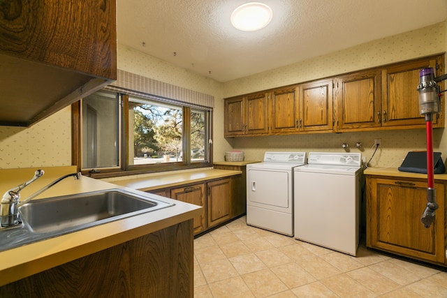 laundry area featuring sink, cabinets, a textured ceiling, washer and dryer, and light tile patterned floors