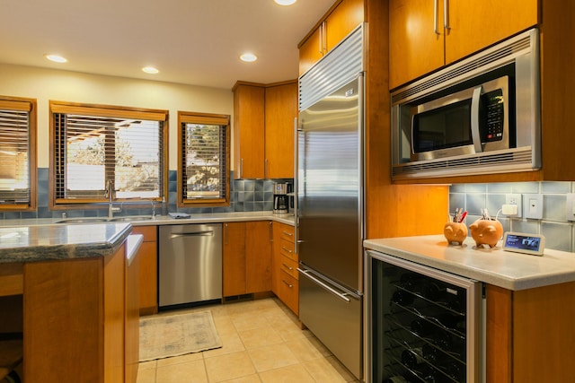 kitchen with appliances with stainless steel finishes, tasteful backsplash, sink, beverage cooler, and light tile patterned floors