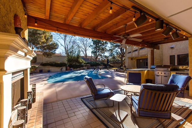 view of patio featuring ceiling fan, area for grilling, exterior bar, and a covered pool