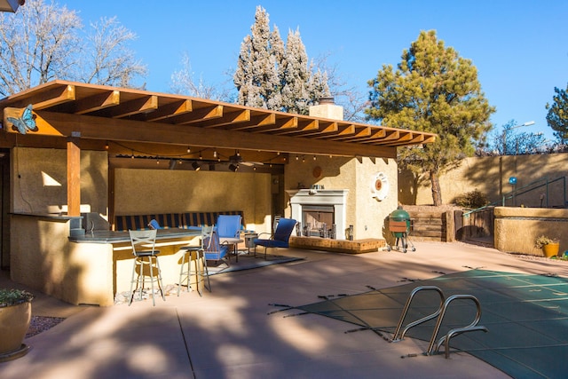 view of patio / terrace with an outdoor fireplace, exterior bar, and grilling area