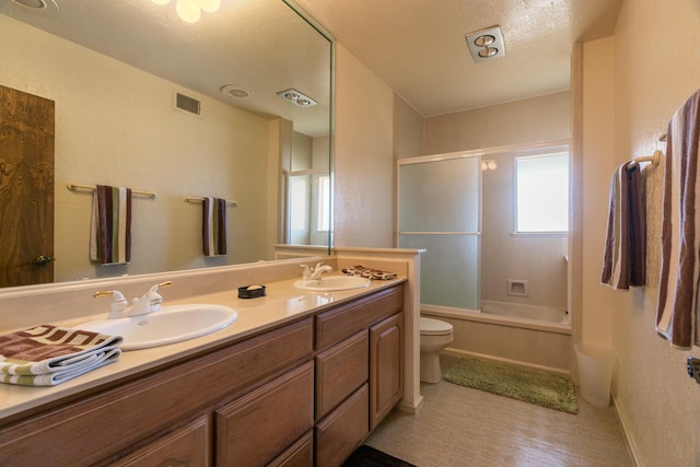 full bathroom with toilet, vanity, bath / shower combo with glass door, and a textured ceiling