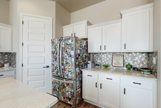 kitchen featuring dark wood-type flooring, decorative backsplash, stainless steel fridge, and white cabinetry