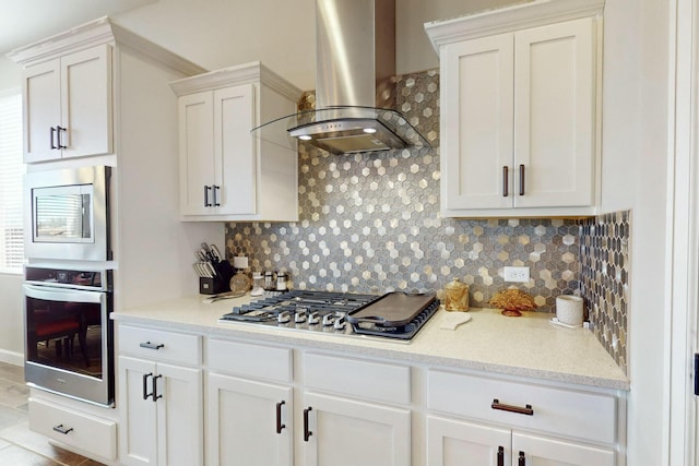 kitchen featuring white cabinets, backsplash, appliances with stainless steel finishes, and wall chimney exhaust hood