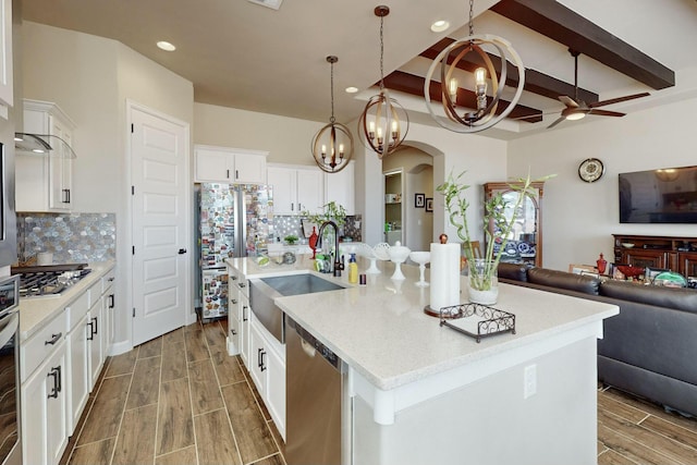 kitchen with tasteful backsplash, appliances with stainless steel finishes, sink, and a center island with sink