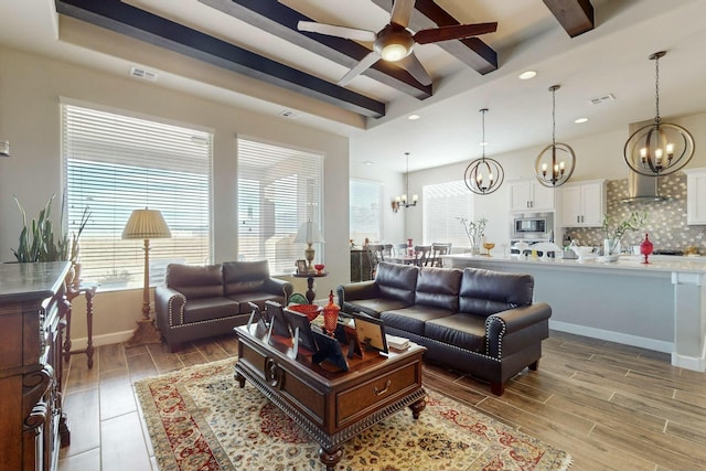 living room with ceiling fan with notable chandelier and beam ceiling