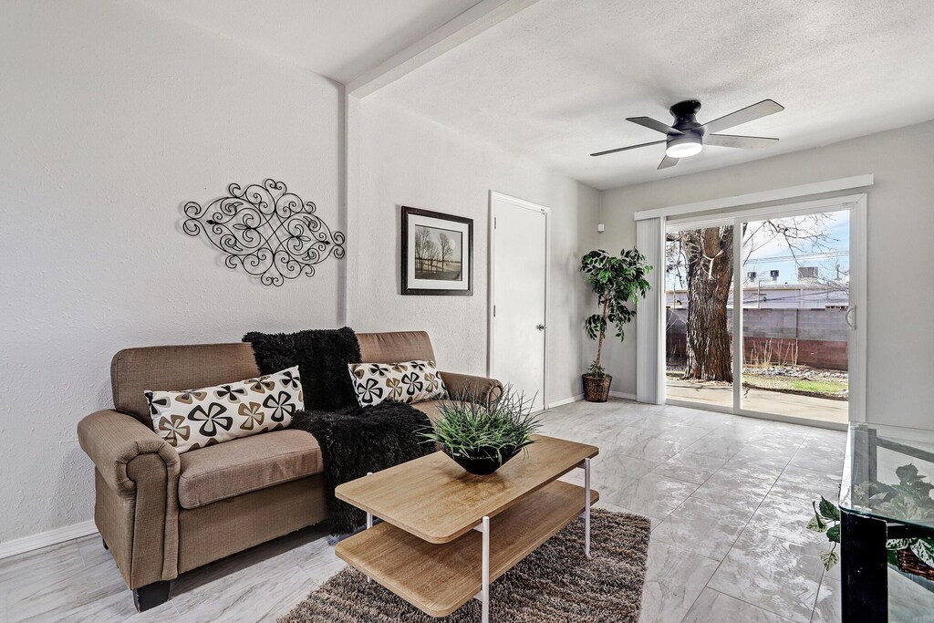 living room featuring ceiling fan, baseboards, and a textured ceiling