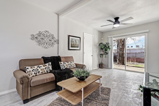 living room featuring ceiling fan, baseboards, and a textured ceiling