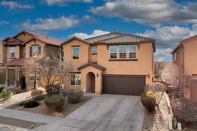 mediterranean / spanish-style house featuring concrete driveway, a tiled roof, an attached garage, and stucco siding