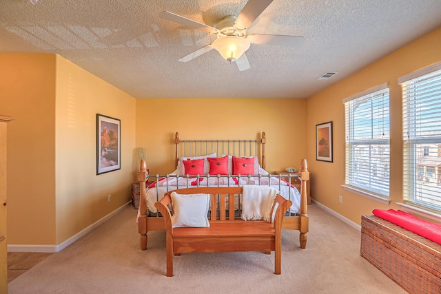 bedroom with visible vents, light carpet, a ceiling fan, a textured ceiling, and baseboards